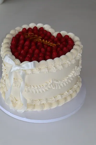 Hvid hjertekage med røde bær og dekorativ frosting