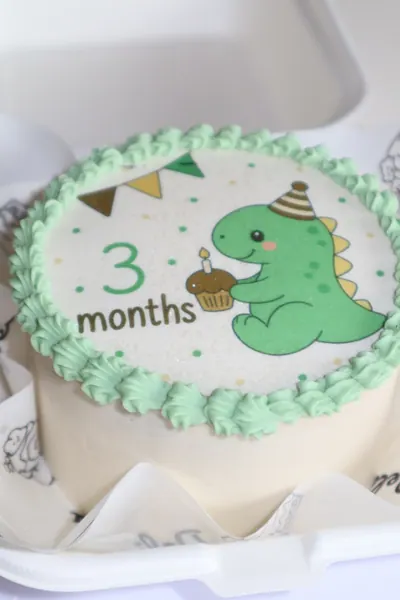 Lys børnekage med grøn dinosaur og grøn dekorativ kant