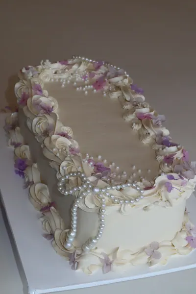 Hvid firkantet kage med blomster, perlekæder og dekorative kanter