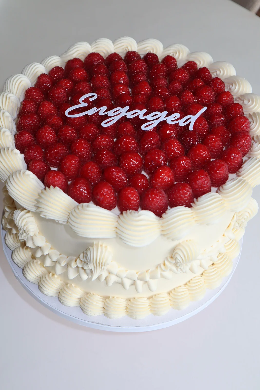 Hvid hjertekage med hindbær og håndsprøjtede detaljer i frosting