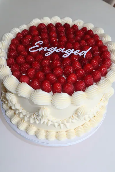 Hvid hjertekage med røde bær og dekorativ frosting