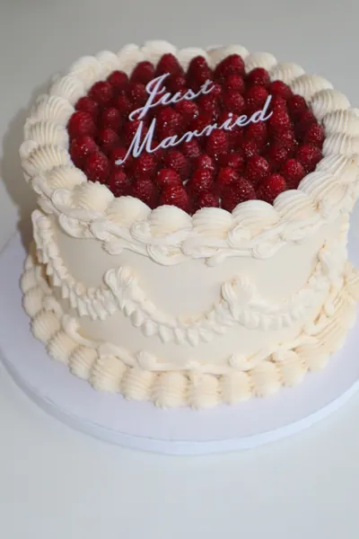 Hvid hjertekage med røde bær og dekorativ frosting