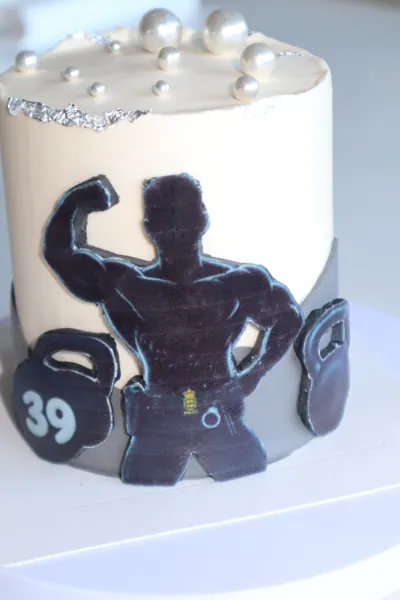 Hvid temakage med vægte og en mørk figur