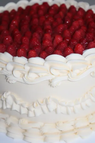 Hvid hjertekage med røde bær og dekorativ frosting