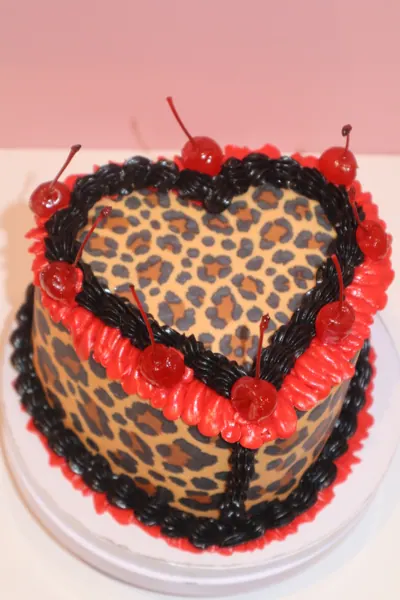 Hjertekage med leopardmønster, røde kirsebær og mørk frosting