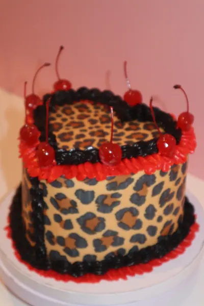 Hjertekage med leopardmønster, røde kirsebær og mørk frosting