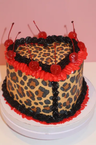 Hjertekage med leopardmønster, røde kirsebær og mørk frosting