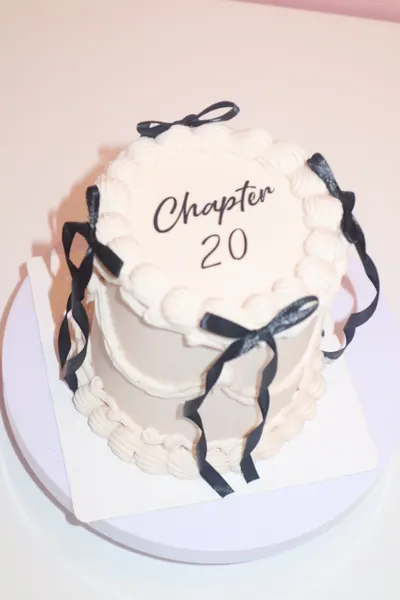 Lys fødselsdagskage med sorte sløjfer og dekorativ frosting