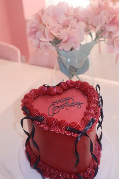 Rød hjertekage med mørke sløjfer og bølgende frosting