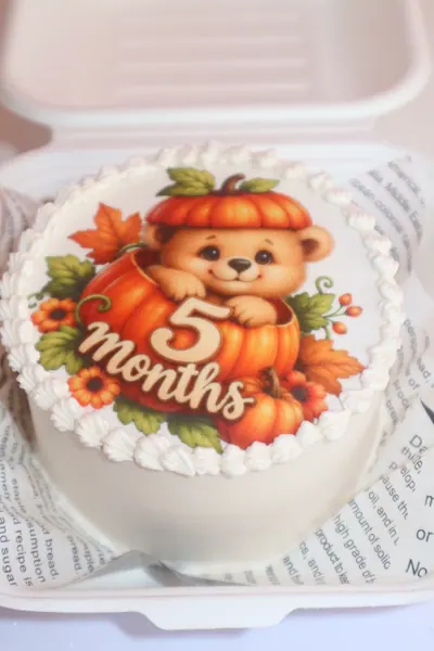 Lille hvid kage med bamse, orange detaljer og personlig dekoration