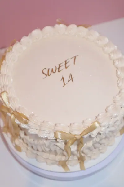 Lys rund kage med gyldne detaljer og dekorativ frosting