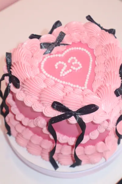 Pink hjertekage med sorte sløjfer og fine detaljer i frosting