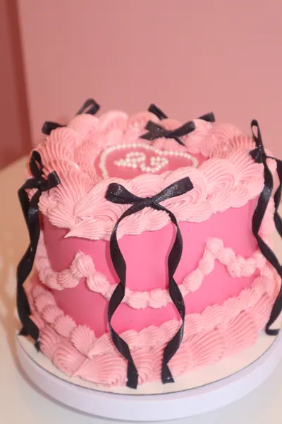 Pink hjertekage med sorte sløjfer og fine detaljer i frosting