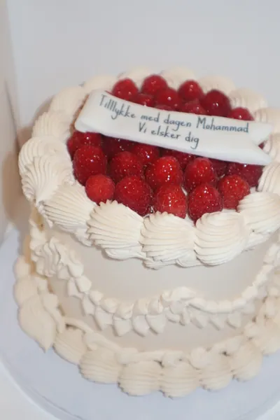 Hvid hjertekage med røde bær og dekorativ frosting