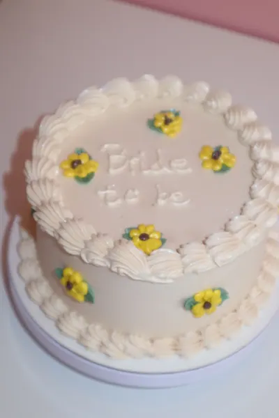Lille hvid kage med gule blomster og dekorativ kant