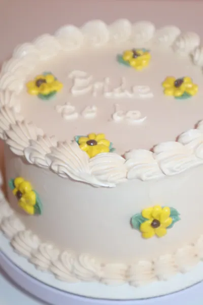 Lille hvid kage med gule blomster og dekorativ kant