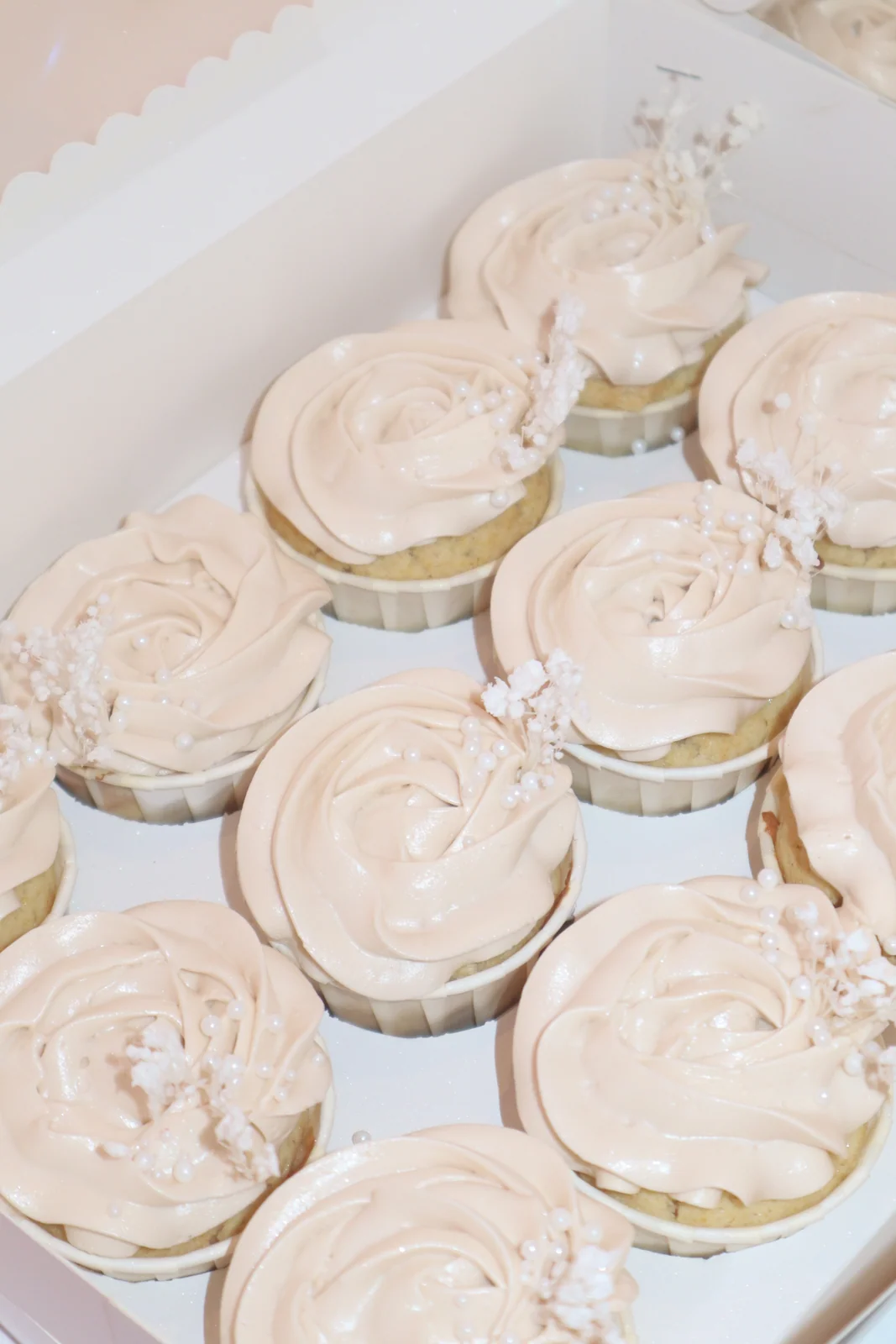 Cupcakes med lys rosa frosting, hvide blomster og perler