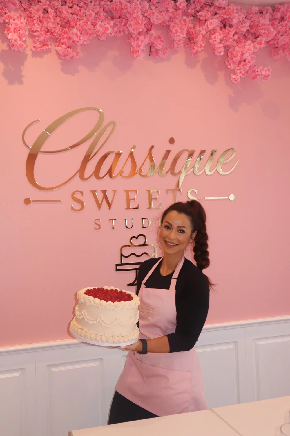 Hawra i sit lyserøde Classique Sweets Studio med en hånddekoreret kage med hindbær.
